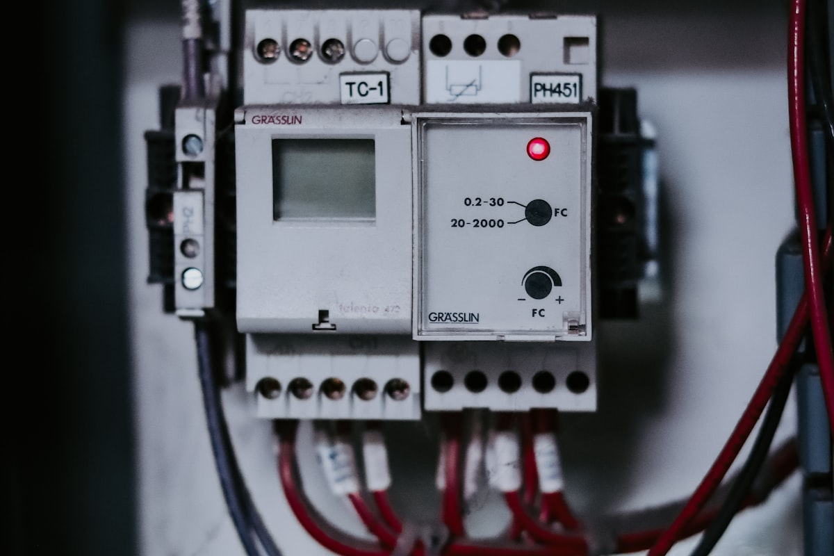 A DIN-rail control relay module with a status LED and screw terminals wired into an industrial control panel - the kind of interposing relay that isolates and protects a PLC output