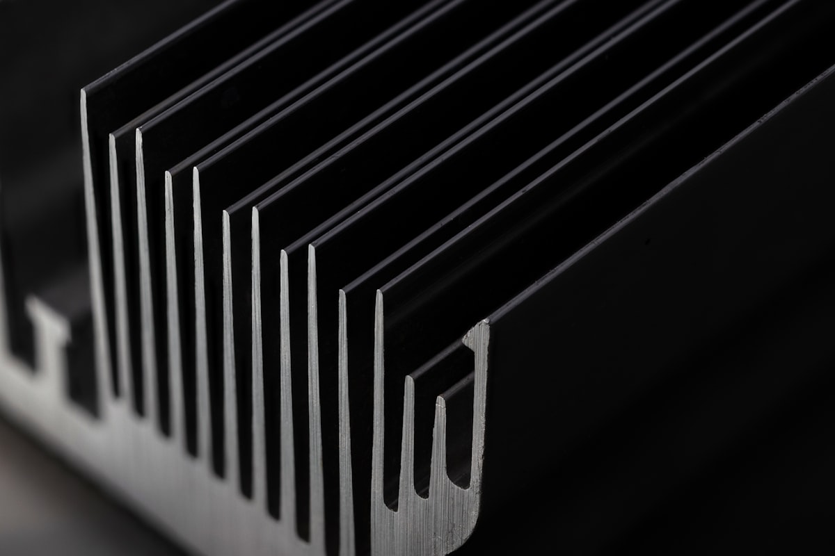 Close-up of a black anodized aluminium heat sink's extruded fins - the thermal hardware that decides whether a solid-state relay's amp rating under IEC 60947-4-3 is real or fiction