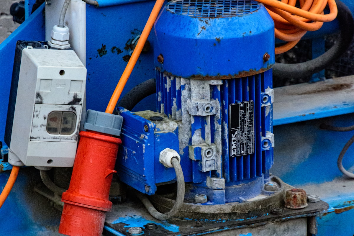 A blue vertically-mounted industrial induction motor with its rating nameplate, driving a pump set - the kind of continuous-duty motor specified by efficiency class, duty type, and ambient derating for Pakistani pumping