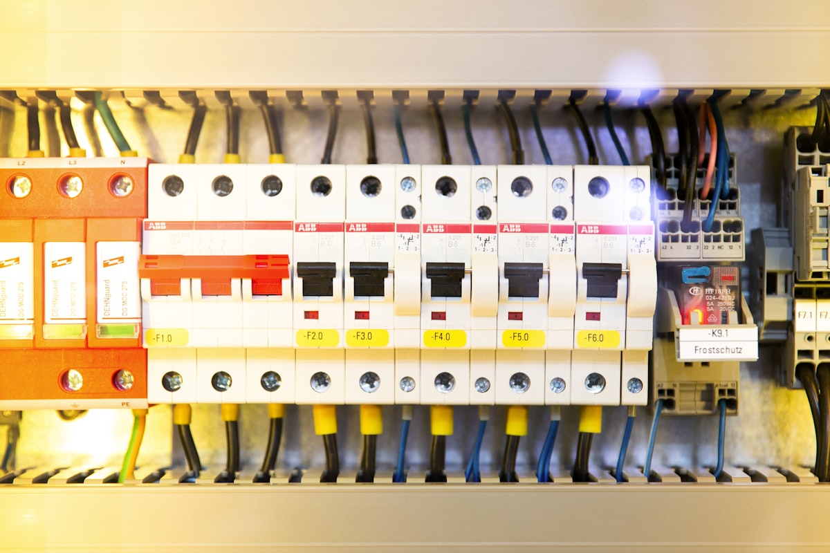 A DIN-rail control panel with breakers, terminal blocks, and a plug-in electromechanical relay in its socket - the switching hardware a specification chooses between EM relays and solid-state under IEC 61810-1 and IEC 60947-4-3
